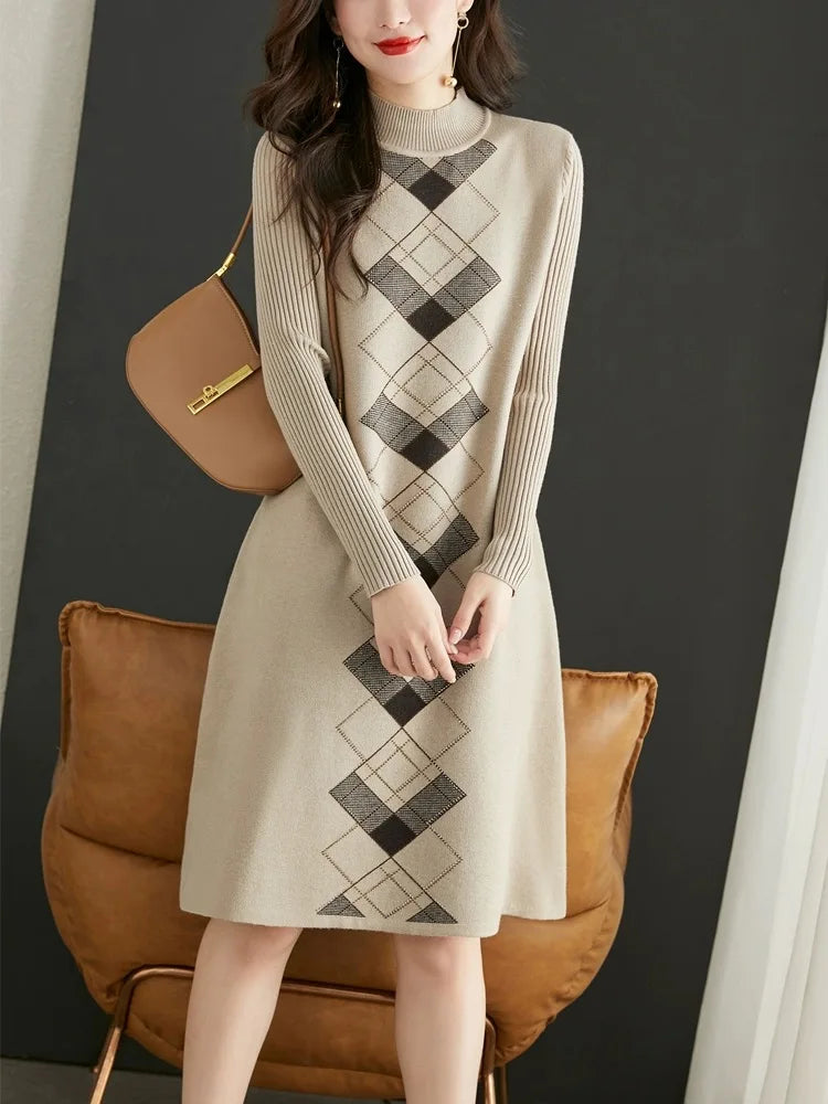 Woman wearing a beige sweater dress with a black and white argyle pattern, standing against a dark background.