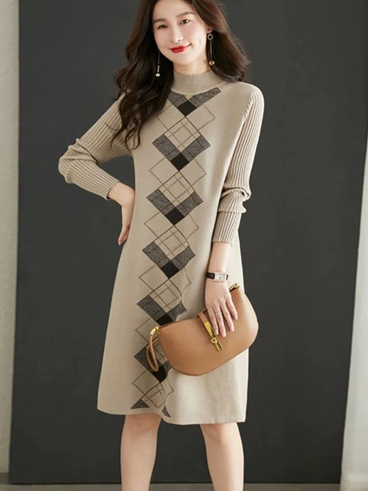 Woman wearing a beige and black patterned dress holding a brown handbag against a dark background